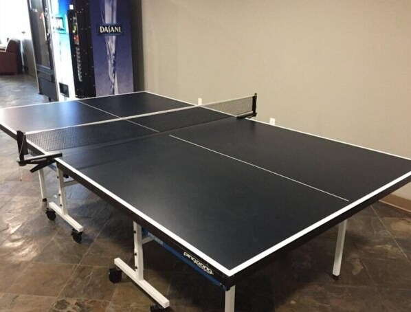 A ping pong table with a net in a room with a tiled floor.