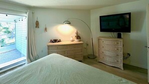 Ein Schlafzimmer mit einem Bett, einem Schminktisch, einem Fernseher und einer Lampe.