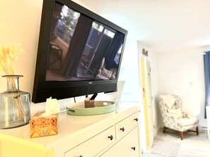 Ein Fernseher auf einem weißen Schrank, dazu eine Vase und eine Taschentuchbox.