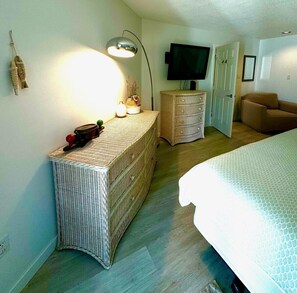 A bedroom with a bed, a dresser, a television, and a lamp.