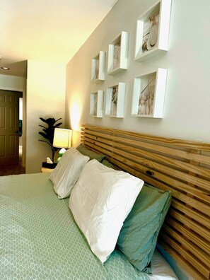 A hotel room with a bed, a nightstand, a lamp, and a wall with framed pictures.