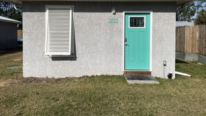 A small, single-story building with a teal door and a white window with blinds. - Aqua Diver is a darling 1 BR house on the East end of Panama City Beach, Florida (Panama City)