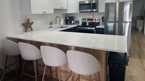 A modern kitchen with white cabinets, stainless steel appliances, and a marble countertop. - Completely Renovated Perfect Beachtown Escape for the Whole Family (Ocean City)