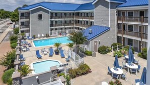 A hotel with a pool area, outdoor seating, and a multi-story building with balconies. - Completely Renovated Perfect Beachtown Escape for the Whole Family (Ocean City)