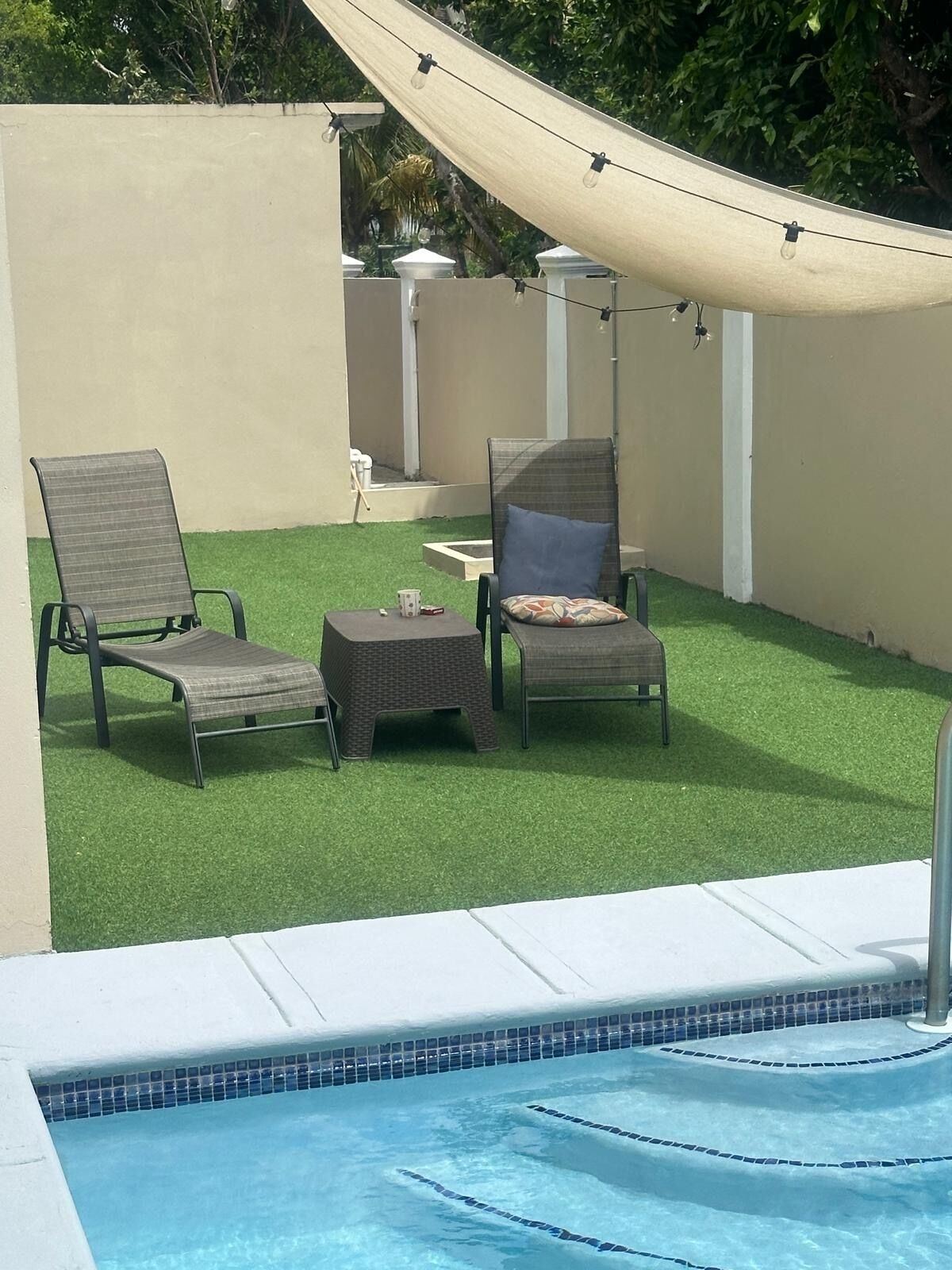 A pool area with two lounge chairs, a small table, and a canopy.