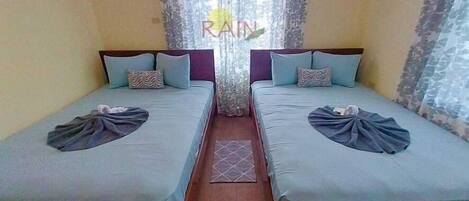 A room with two single beds, each with a pillow and a blanket.