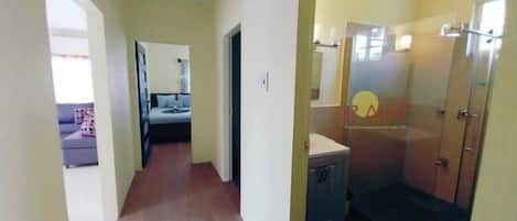 Un pasillo estrecho con una cama y un baño a la derecha.