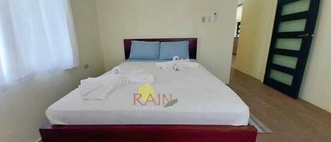 Un lit bien fait, avec un matelas blanc et une tête de lit en bois.