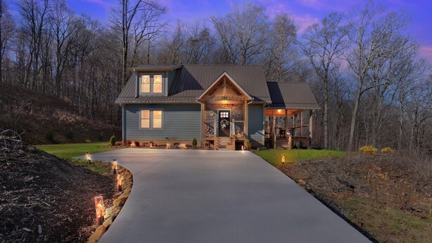Une maison à deux étages avec un porche à l’avant, un garage et une allée menant à l’entrée.
