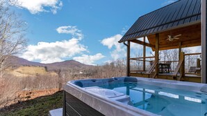 Un bain à remous avec une terrasse en bois et une vue sur les montagnes.
