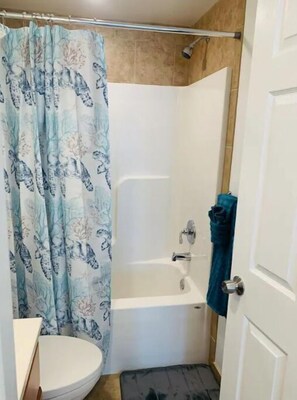 Bathroom features a shower, bathtub, and nature-themed shower curtain.