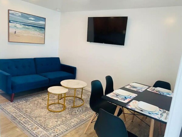 Cozy living space with a sofa, flat-screen TV, and dining area for four.