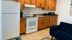 Una cocina compacta con armarios de madera, un refrigerador blanco, estufa y microondas.