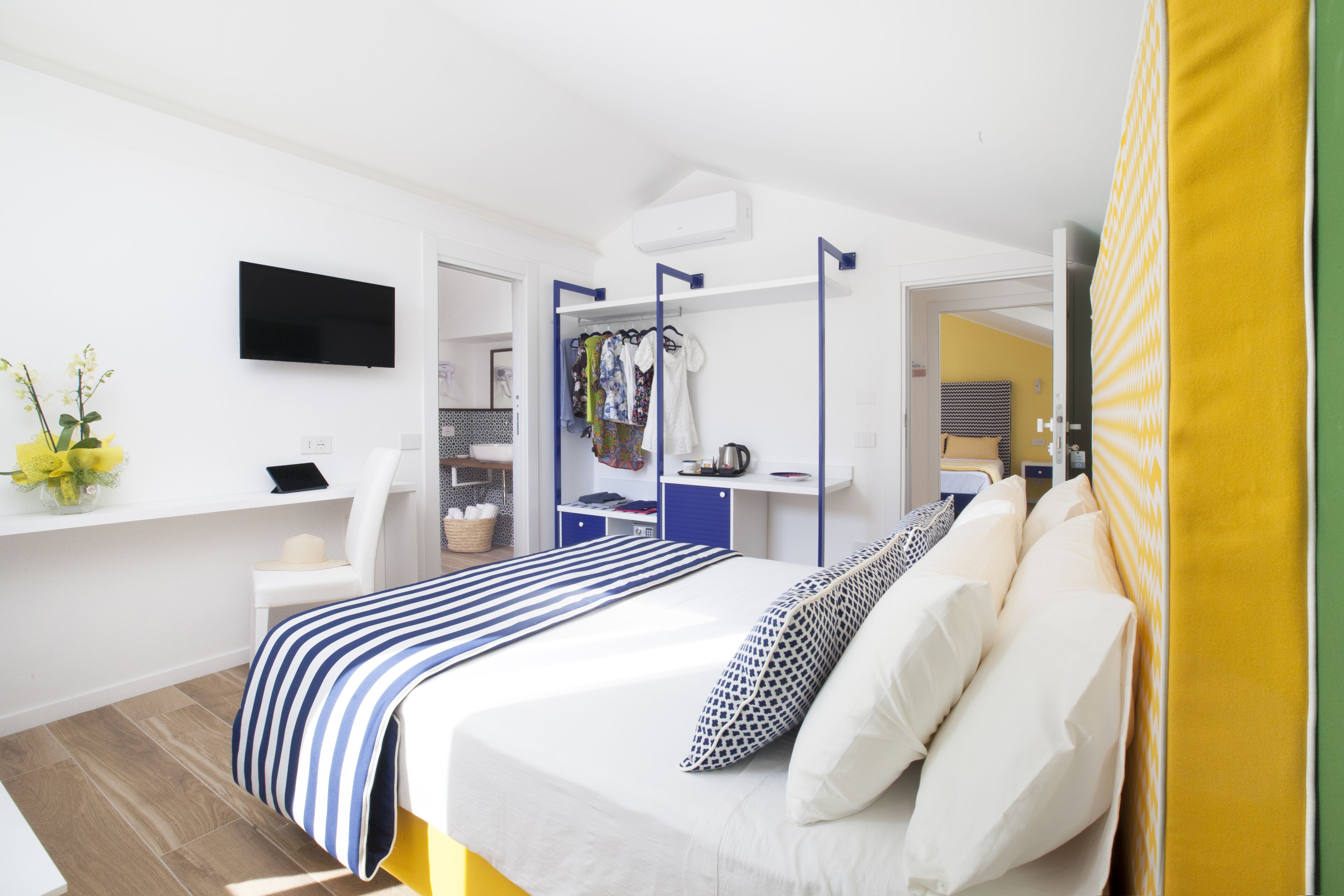A modern hotel room with a bed, a desk, a TV, and a wardrobe.