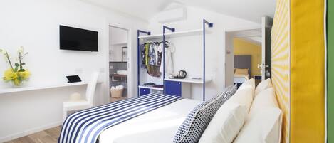 A modern hotel room with a bed, a desk, a TV, and a wardrobe.