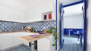 A modern kitchen with white cabinets, a wooden countertop, and a patterned backsplash. - Relais Loggia Li Galli (Massa Lubrense)