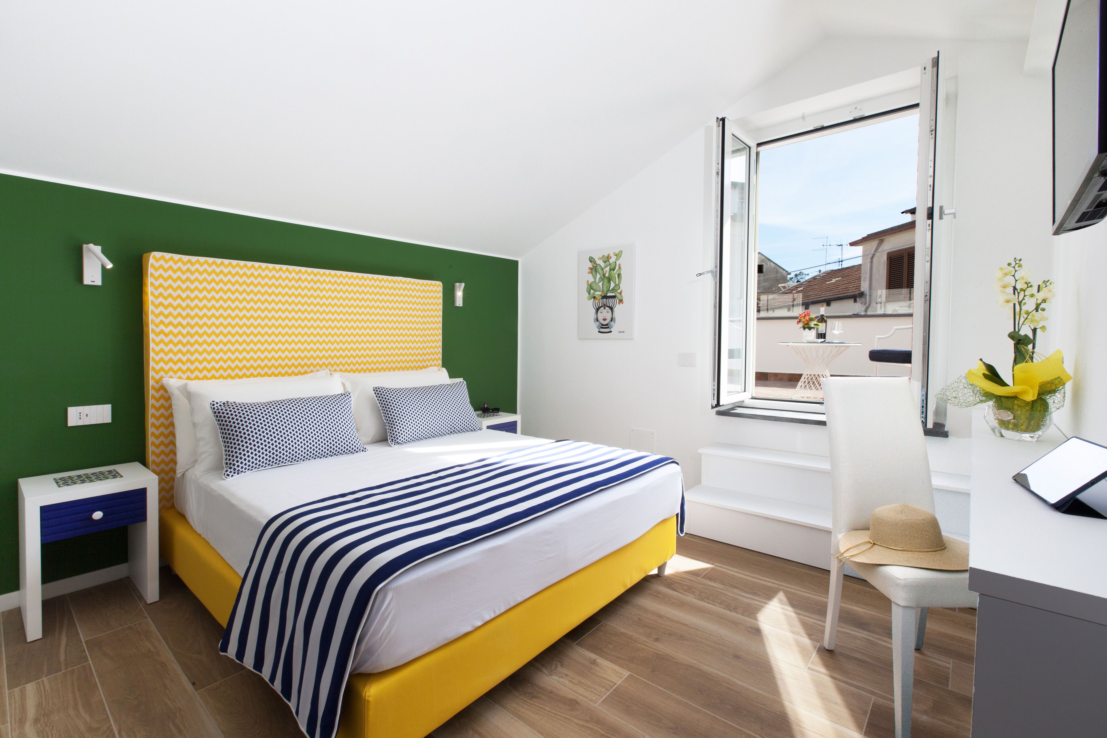 A modern bedroom with a bed, bedside table, and a window with a view of buildings.