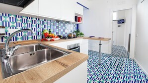 A modern kitchen with a stainless steel sink, wooden countertop, and a patterned backsplash. - Relais Loggia Li Galli (Massa Lubrense)
