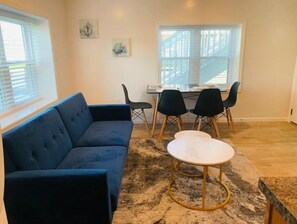 Relax in this stylish living room with a sofa, dining area, and artwork.