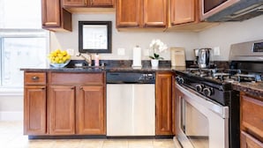 Una cocina moderna con armarios de madera, lavavajillas de acero inoxidable, estufa y cafetera.