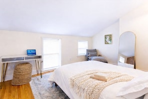 Une chambre à coucher avec un lit, un bureau, une chaise, une fenêtre et un miroir.