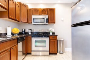 Una cocina con armarios de madera, electrodomésticos de acero inoxidable, una cafetera y un cubo de basura.