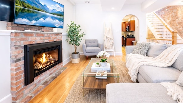 Una sala de estar con chimenea, televisor, sofá y escalera.