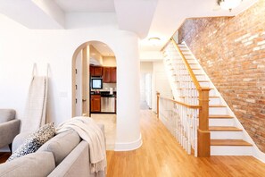 Un salon moderne avec un canapé, une cheminée et un escalier menant à un espace cuisine.