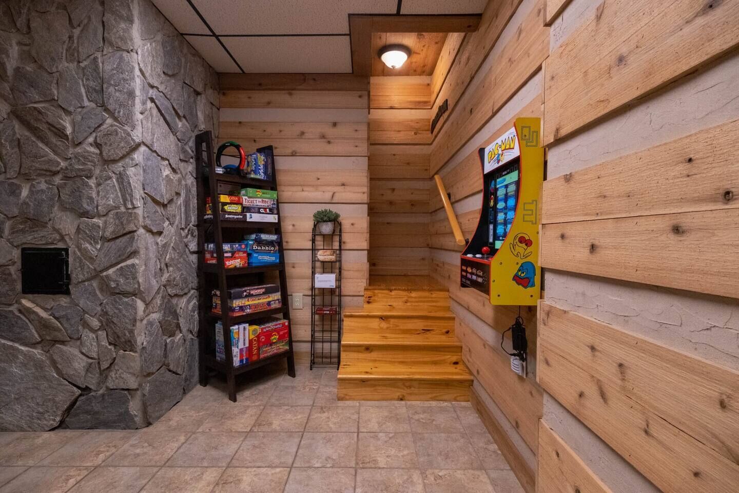 Un intérieur en bois avec un mur en pierre, une bibliothèque et une borne d’arcade Pac-Man.