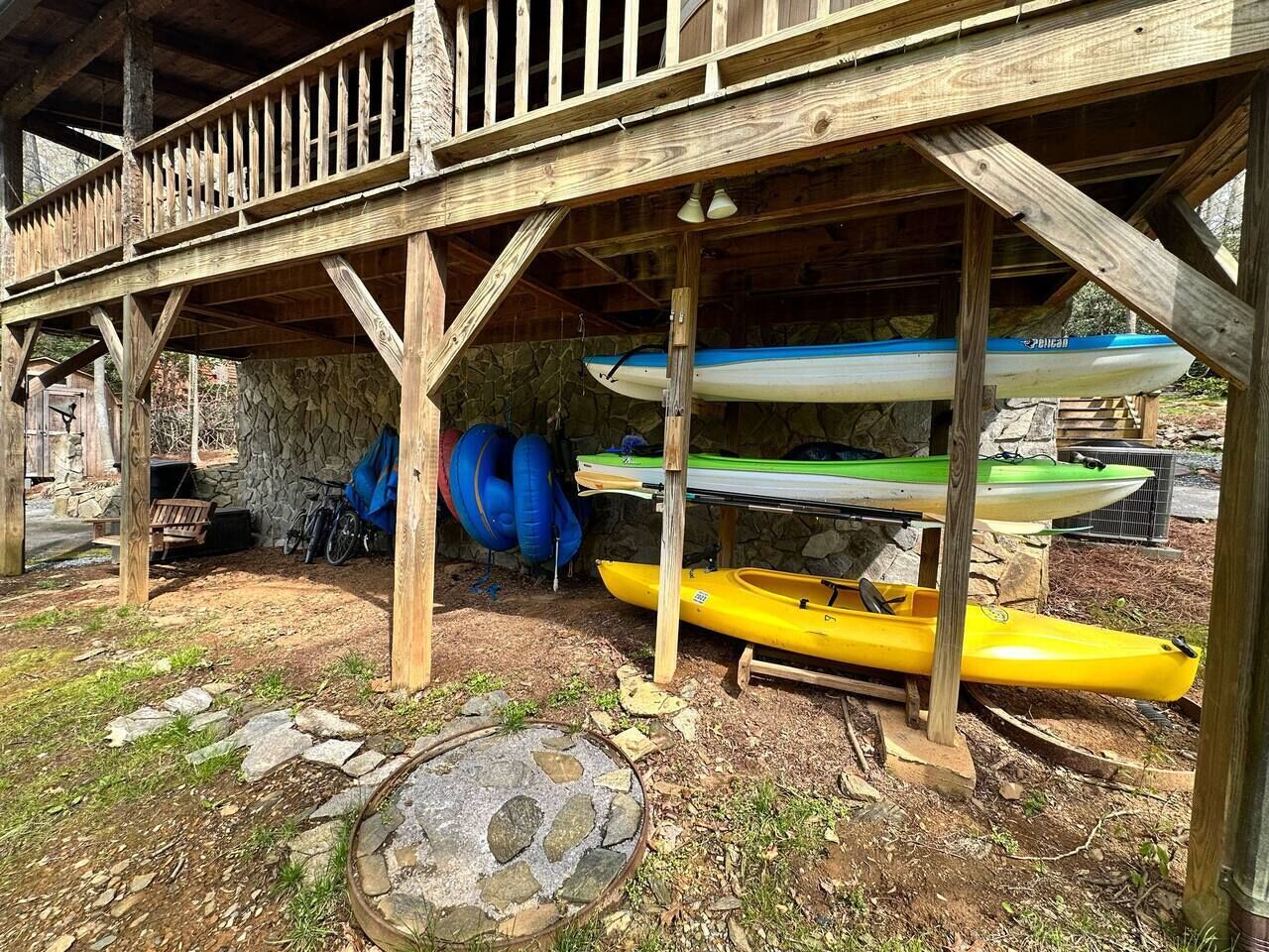 A covered wooden structure with kayaks and a bicycle.