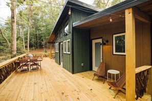 Un patio in legno con tavolo e sedie, un portico coperto e una porta con una finestra.