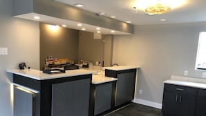 A modern kitchen with dark cabinetry, a central island, and a large mirror above the sink. - Jackson motel  (Murfreesboro)