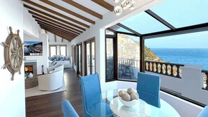 Ein modernes Wohnzimmer mit Glastisch, blauen Stühlen und Meerblick.