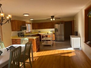 Kitchen area with a central island, stainless steel refrigerator, and dining table.