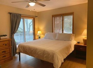 Relax in this serene bedroom with a large bed, ceiling fan, and window with blinds.
