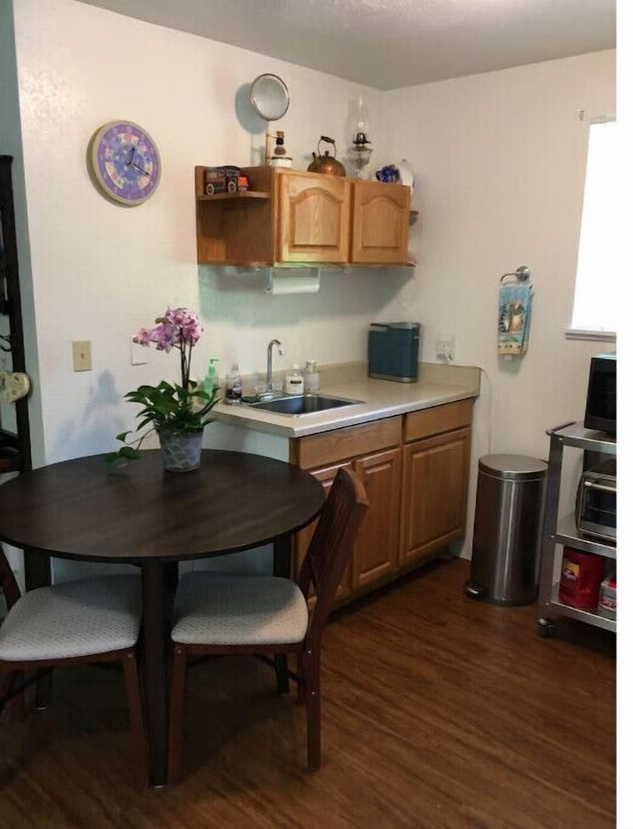 A compact kitchen with wooden cabinets, a sink, and a dining table with chairs.