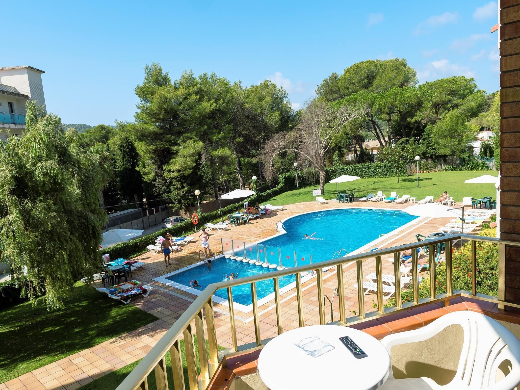A pool area with a curved pool, lounge chairs, and umbrellas.