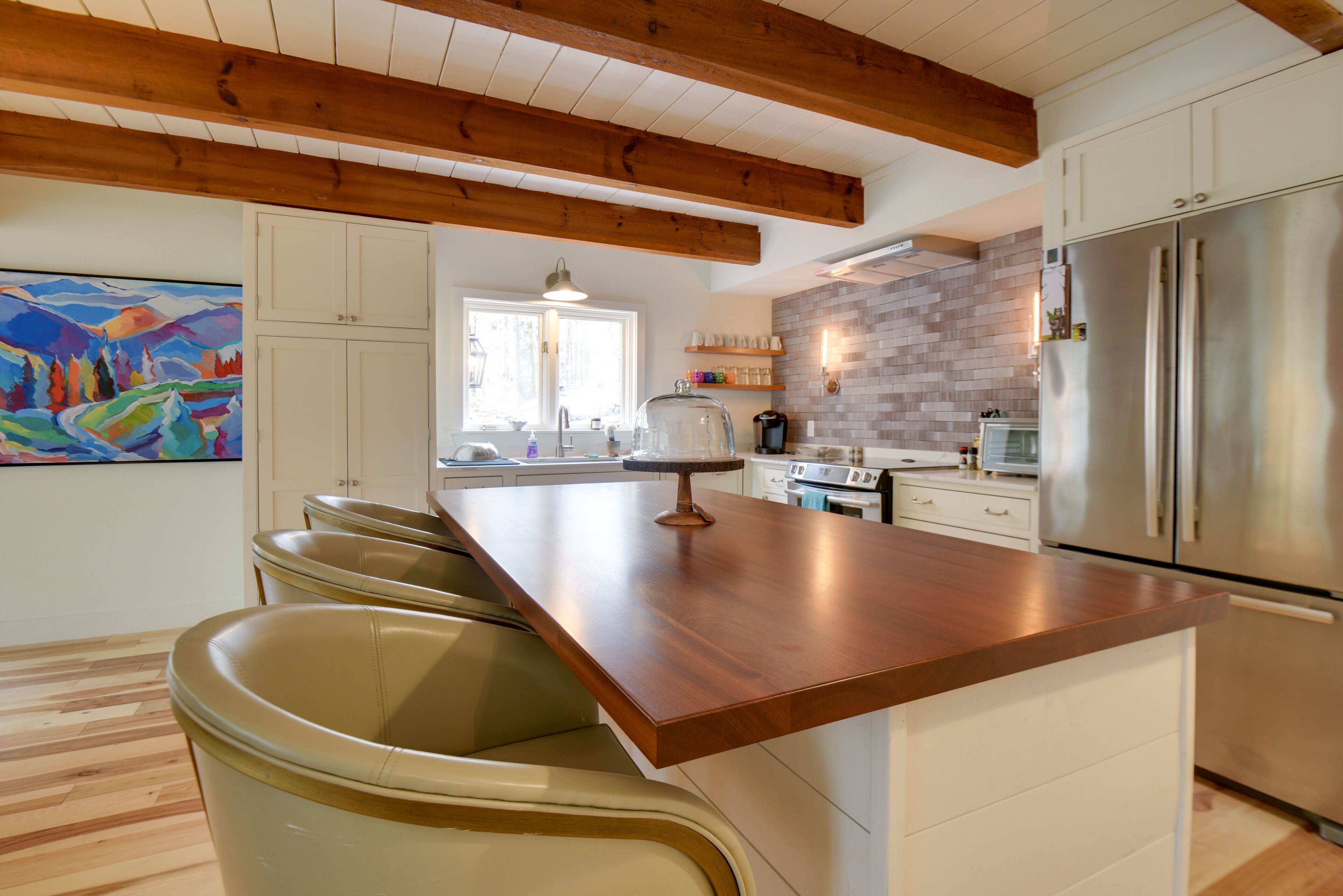 Una cocina moderna con techo de madera, electrodomésticos de acero inoxidable y una isla central con taburetes de bar.