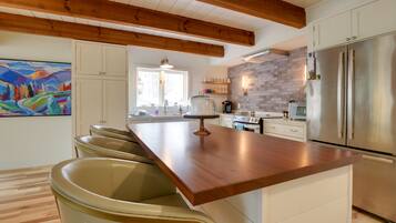 Una cocina moderna con techo de madera, electrodomésticos de acero inoxidable y una isla central con taburetes de bar.