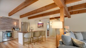 A modern kitchen with a central island, wooden beams, and a dining area with chairs. - Private Hot Tub & Deck: North Conway Retreat (North Conway)