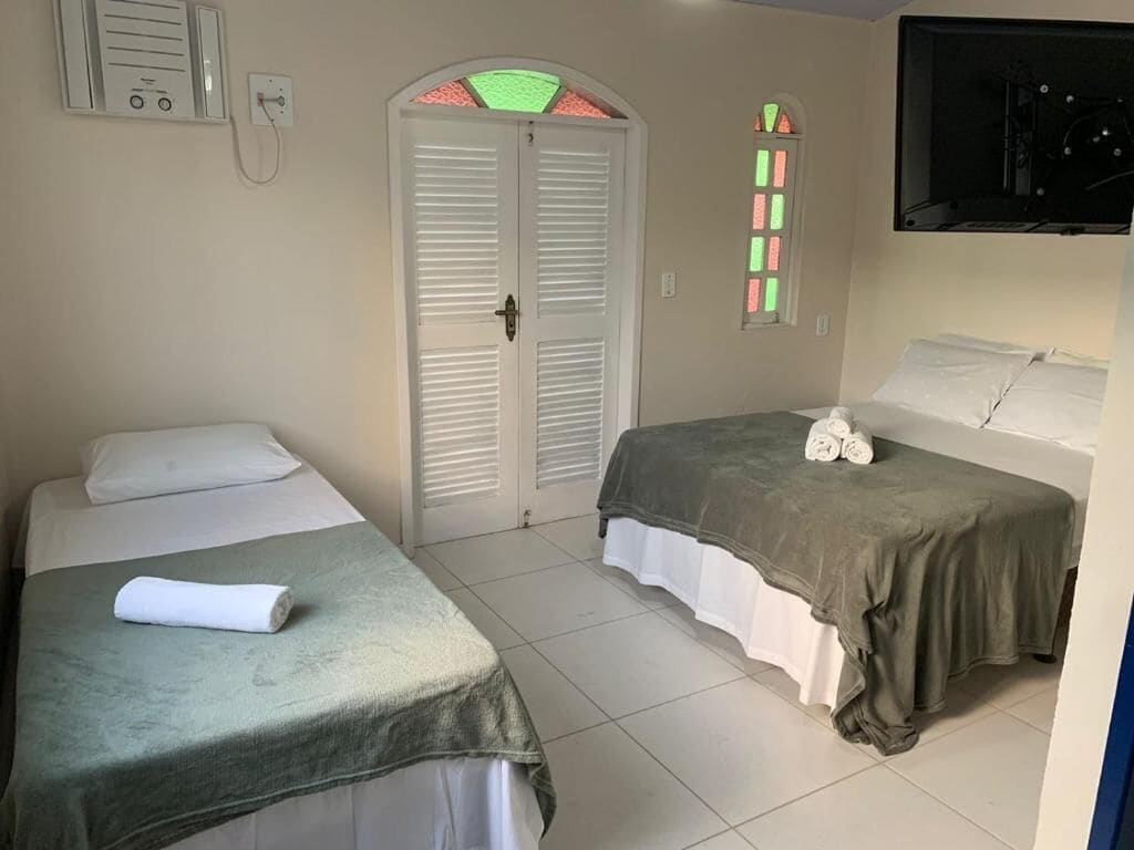 Une chambre d’hôtel avec deux lits, une armoire, une télévision et une fenêtre ornée de vitraux.