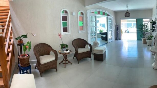 Un amplio salón con mobiliario de mimbre, una escalera y vistas al exterior.
