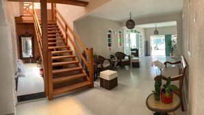 Un amplio salón con una escalera de madera, una mesa de comedor y diferentes disposiciones de asientos.