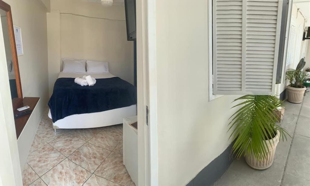 Ein Schlafzimmer mit einem Bett, Kissen, einer Decke und einer Fernbedienung auf einem Nachttisch.