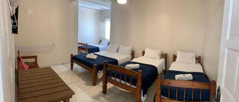 Una habitación con cuatro camas de madera, una mesa de madera y un ventilador de techo.