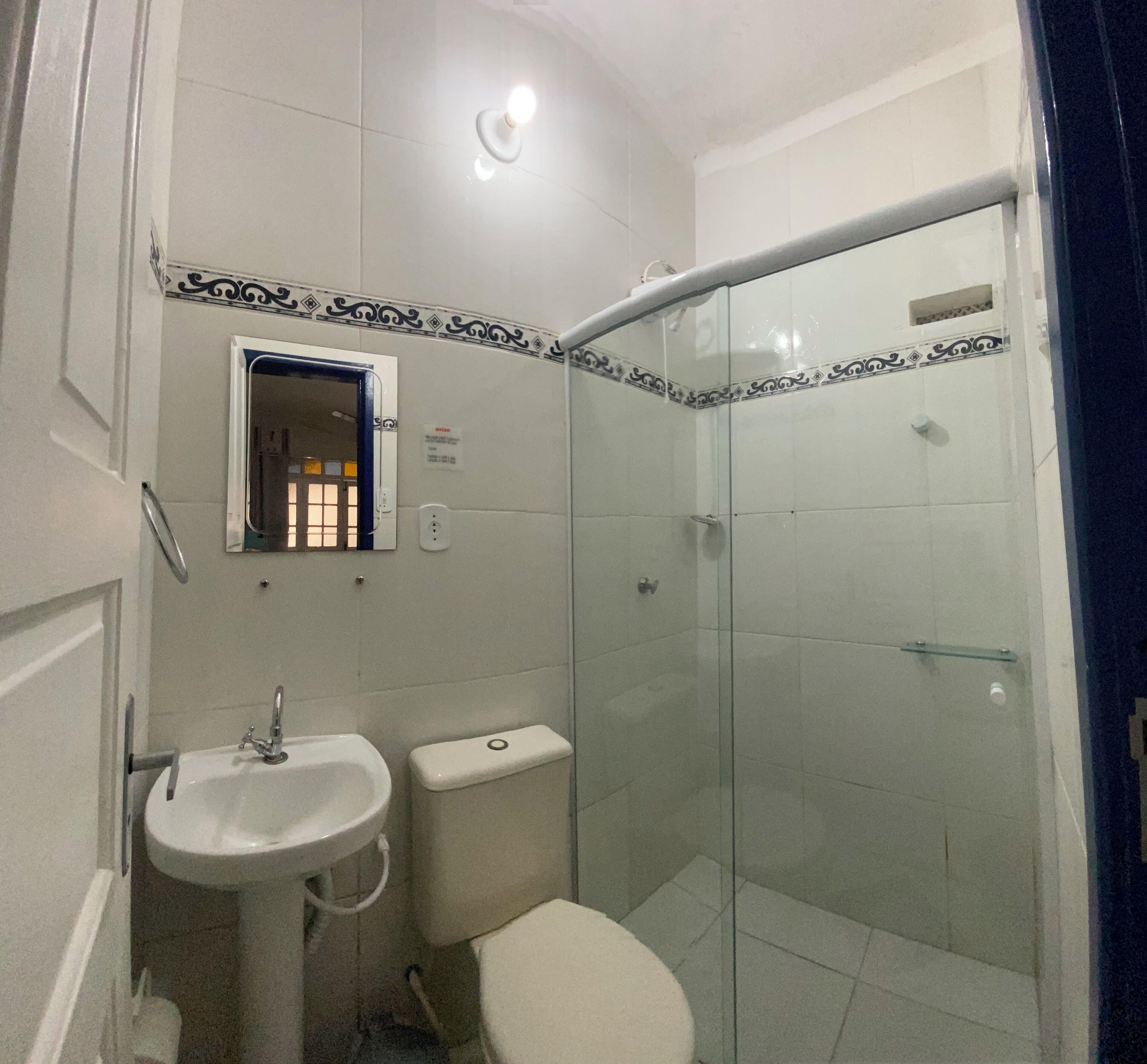 Un baño con lavamanos, inodoro y cabina de ducha con mampara de vidrio.