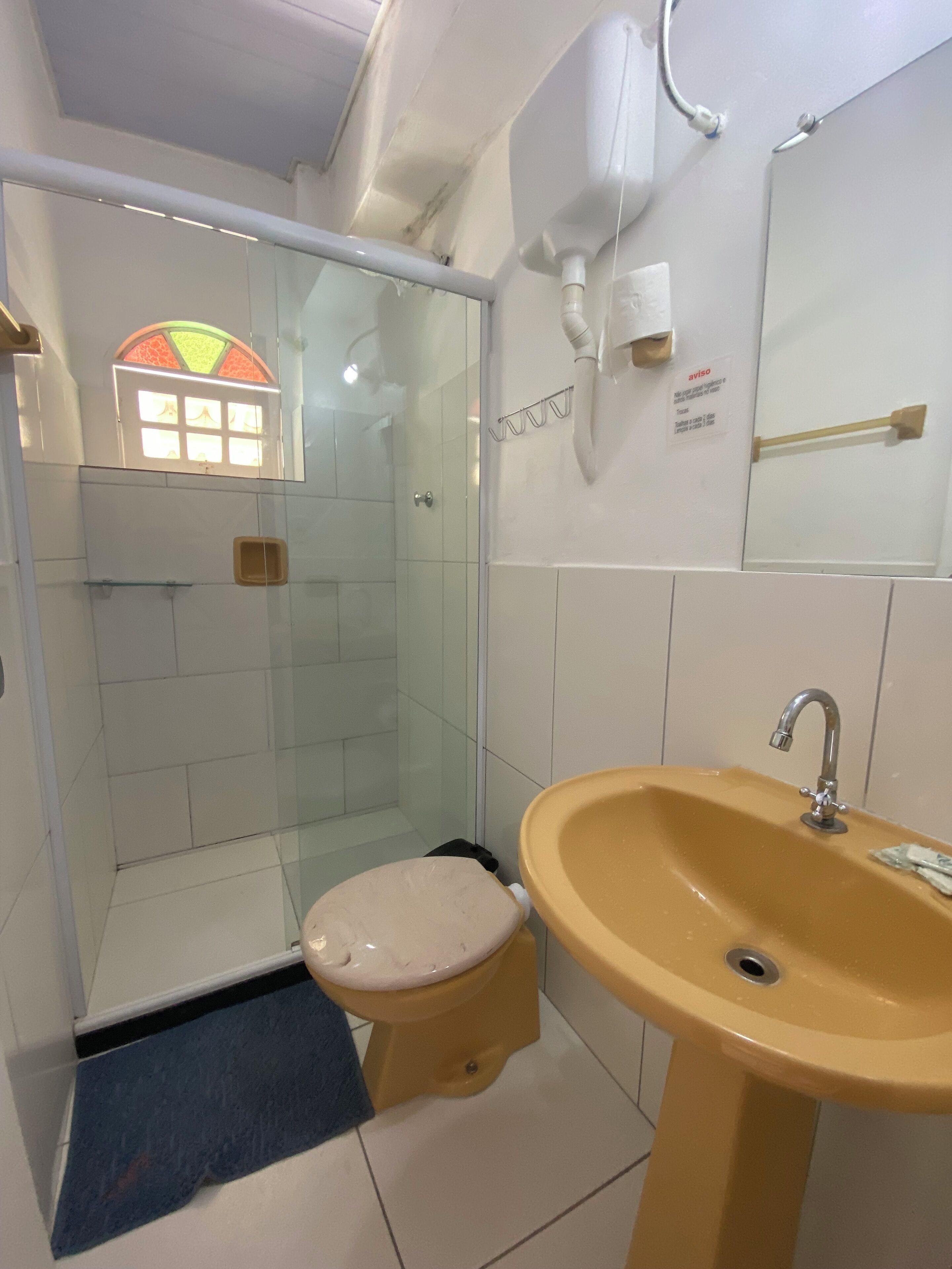 A bathroom with a glass shower enclosure, a toilet, and a sink.