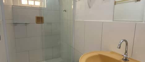 A bathroom with a glass shower enclosure, a toilet, and a sink.