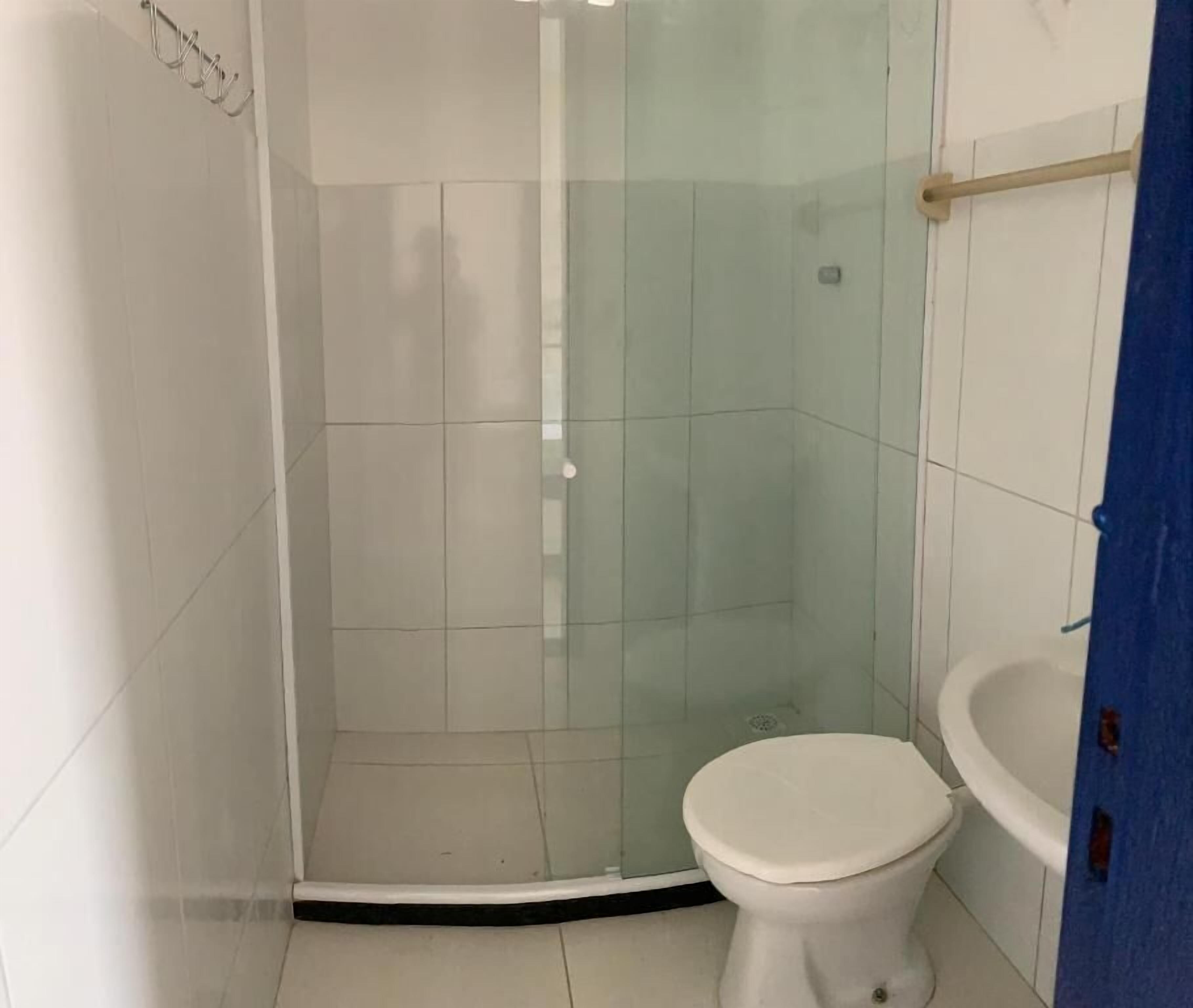 Un baño con ducha de mampara de vidrio, inodoro y lavamanos blancos.