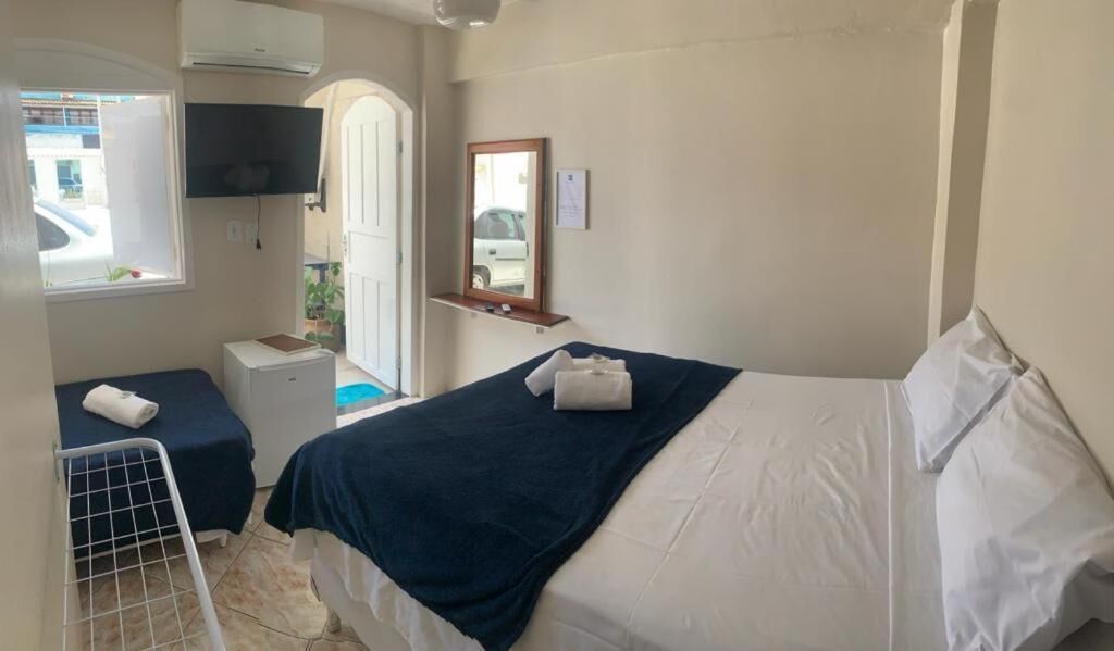 Une chambre d’hôtel avec un lit, un petit bureau, une chaise, une télévision et une fenêtre.